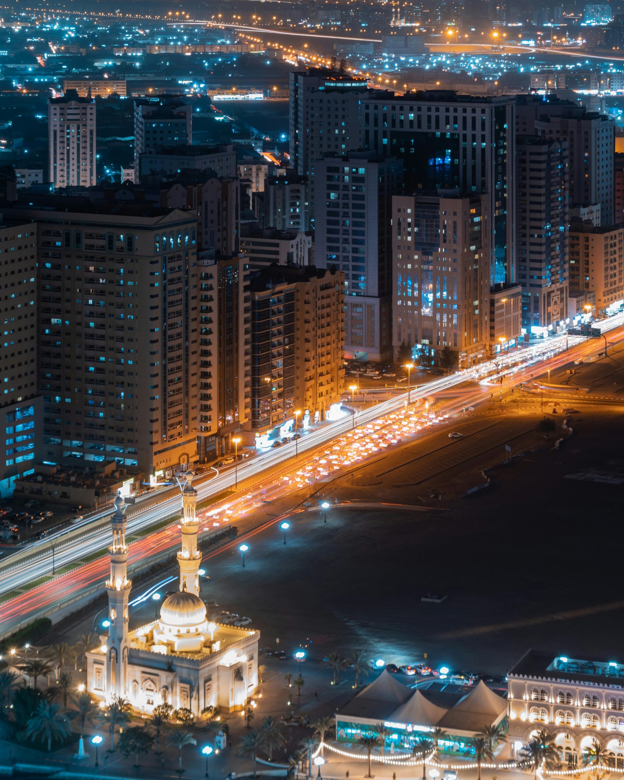 Stunning aerial view of Sharjah cityscape with vibrant lights and bustling traffic at night.